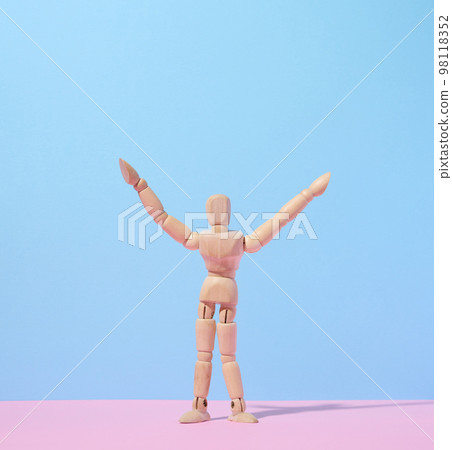 Wooden puppet man on a blue background, arms raised up 98118352