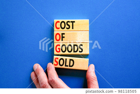 COGS cost of goods sold symbol. Concept words COGS cost of goods sold on wooden block on beautiful blue background. Businessman hand. Business COGS cost of goods sold concept. Copy space. 98118505