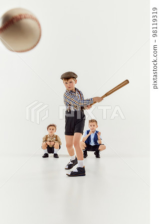 Boys, children in classical retro clothes playing baseball over grey studio background. Hitting. Competition. Concept of game, childhood, friendship 98119319