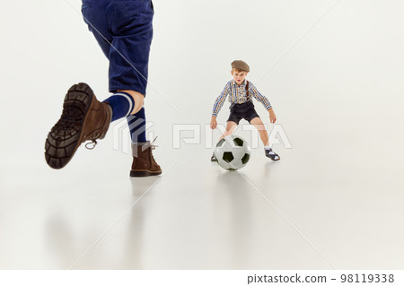 Goalkeeper. Boys, children in classical retro clothes playing football over grey studio background. Concept of game, childhood, friendship 98119338