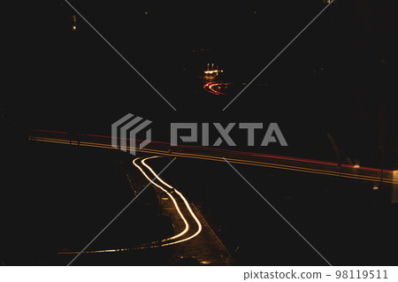 A dark city street at night and car headlights on a long exposure. A blackout in Kyiv due to the russian war in Ukraine. A global social problem with electricity. Darkness over town. Cars on roads. 98119511