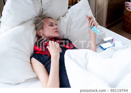 Young woman takes her body temperature and looks at the thermometer 98119704