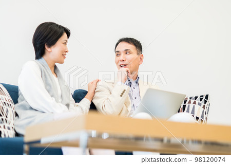 Middle-aged couple looking at a computer in the living room Middle-aged couple looking at a computer in the living room 98120074