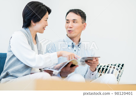A middle-aged couple looking at a magazine in the living room A middle-aged couple looking at a magazine in the living room 98120401