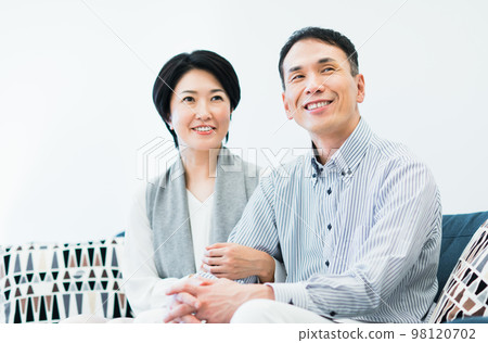 Middle couple relaxing in the living room Middle couple relaxing in the living room 98120702