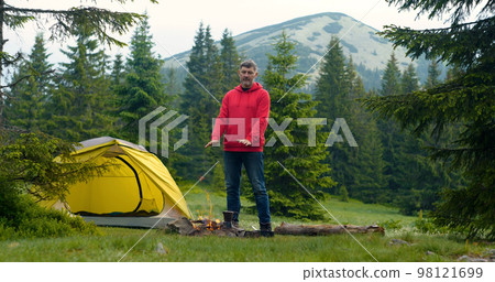Bearded man near a fire in the mountains Bearded man near a fire in the mountains 98121699