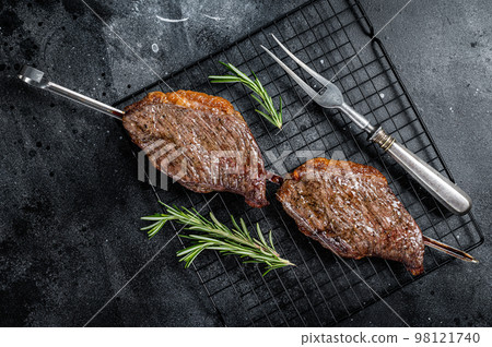 Picanha, traditional Brazilian barbecue, grilled beef meat steak. Black background. Top view Picanha, traditional Brazilian barbecue, grilled beef meat steak. Black background. Top view 98121740