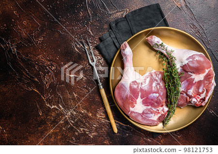 Raw duck legs. Poultry meat ready to cook. Dark background. Top view. Copy space 98121753
