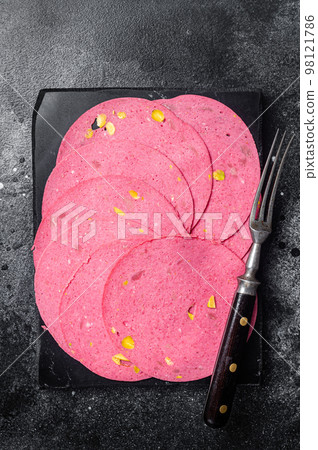 Slices of meat salami sausage with pistachios nuts on marble board. Black background. Top view 98121786