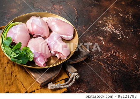 Free range Raw Boneless and skinless Chicken leg thigh fillet with spices. Dark background. Top view. Copy space 98121798