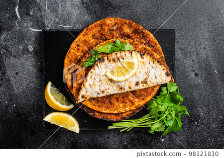 Lahmacun traditional Turkish pizza and wraps with salad on marble board with spices. Black background. Top view Lahmacun traditional Turkish pizza and wraps with salad on marble board with spices. Black background. Top view 98121810
