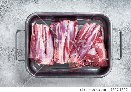 Fresh Raw lamb shanks meat in a steel tray. White background. Top view 98121822