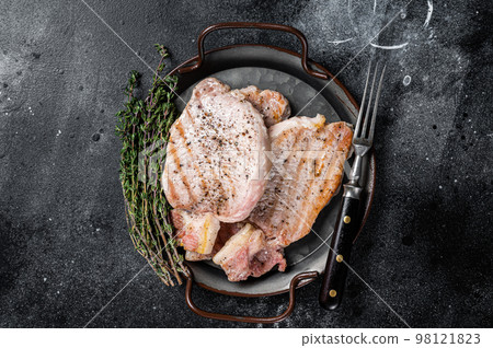 Grilled delicious pork chop steaks with herbs and spices. Black background. Top view Grilled delicious pork chop steaks with herbs and spices. Black background. Top view 98121823