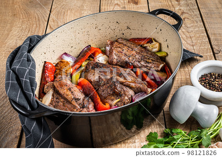 Roasted slow cooked lamb shanks with vegetables and herbs. Wooden background. Top view Roasted slow cooked lamb shanks with vegetables and herbs. Wooden background. Top view 98121826