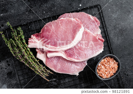 Raw pork cutlet chop steak for fry on pan with herbs. Black background. Top view 98121891