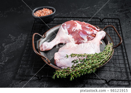Raw Free range duck legs in a steel tray with thyme. Black background. Top view Raw Free range duck legs in a steel tray with thyme. Black background. Top view 98121915