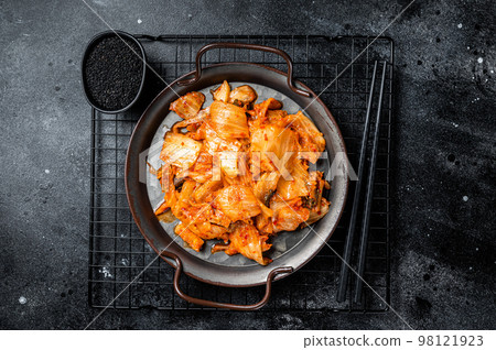 Chinese cabbage kimchi in black dish, Korean cuisine. Black background. Top view Chinese cabbage kimchi in black dish, Korean cuisine. Black background. Top view 98121923