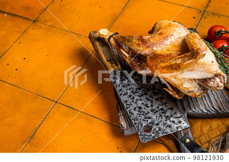 Grilled guinea fowl with herbs and spices on butcher board, cooked game bird. Orange background. Top view. Copy space Grilled guinea fowl with herbs and spices on butcher board, cooked game bird. Orange background. Top view. Copy space 98121930