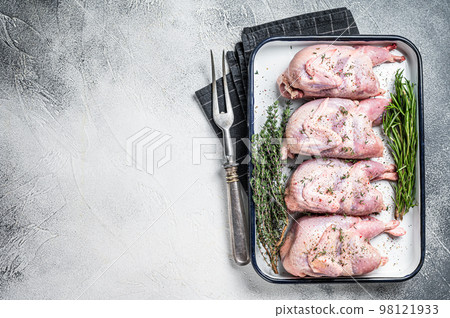 Raw quail meat with spices, garlic and herbs ready to cooking in baking dish. White background. Top view. Copy space Raw quail meat with spices, garlic and herbs ready to cooking in baking dish. White background. Top view. Copy space 98121933