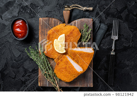 Viennese veal escalope, fried meat Schnitzel steak. Black background. Top view Viennese veal escalope, fried meat Schnitzel steak. Black background. Top view 98121942