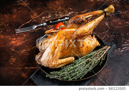 Roast guinea fowl with herbs and spices, cooked game bird. Dark background. Top view 98122005