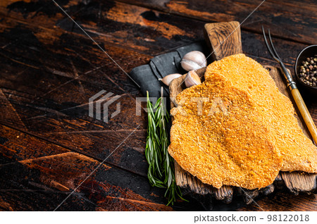 Uncooked Wiener schnitzel in breadcrumbs, raw pork meat. Wooden background. Top view. Copy space Uncooked Wiener schnitzel in breadcrumbs, raw pork meat. Wooden background. Top view. Copy space 98122018