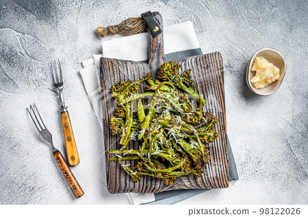 Baked Broccolini cabbage Sprouts with parmesan cheese on wooden board. White background. Top view Baked Broccolini cabbage Sprouts with parmesan cheese on wooden board. White background. Top view 98122026