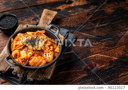 Kimchi salted and fermented chinese cabbage in a skillet. Wooden background. Top view. Copy space 98122027