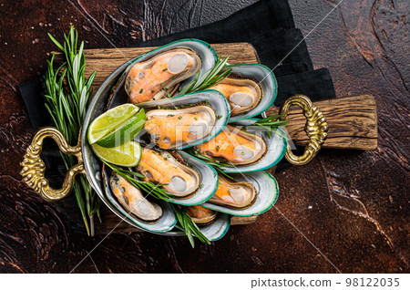 Steamed cooked Green mussels with herbs and spices in a skillet. Dark background. Top view 98122035