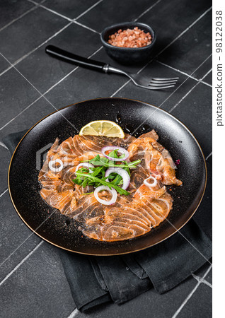 Fresh Salmon carpaccio with onion and arugula on a plate. Black background. Top view Fresh Salmon carpaccio with onion and arugula on a plate. Black background. Top view 98122038