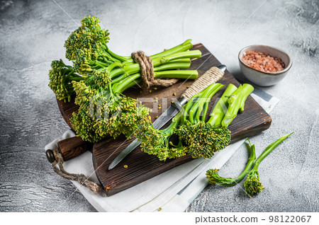 Fresh bunch of Broccolini sprouts on cutting board ready for cookining. White background. Top view 98122067