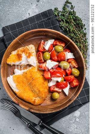 Fried tilapia fillet on a plate with salad. Gray background. Top view 98122152