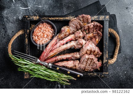 Grilled lamb chop steak, mutton meat cutlet in wooden tray. Black background. Top view Grilled lamb chop steak, mutton meat cutlet in wooden tray. Black background. Top view 98122162