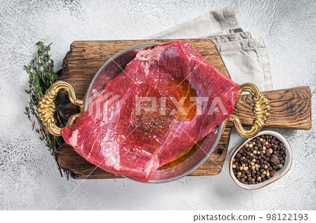 Flap or flank steak, raw beef meat in skillet with herbs and olive oil. White background. Top view 98122193