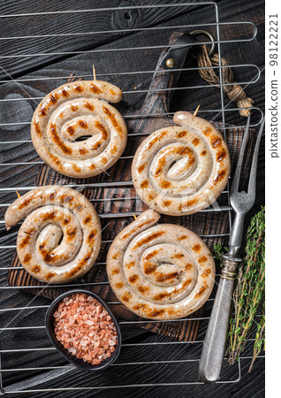 BBQ grilled spiral pork meat sausages on a grill. Black background. Top view BBQ grilled spiral pork meat sausages on a grill. Black background. Top view 98122221