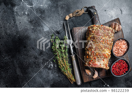 Uncooked spicy pork meat roulade prepared to roast with herbs and spices. Black background. Top view. Copy space 98122239