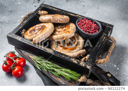 Grilled spiral pork meat sausages in a tray with herbs. Gray background. Top view 98122274