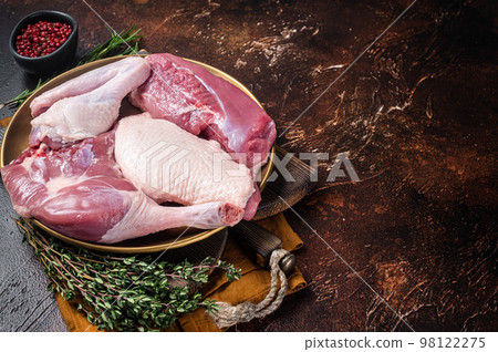 Fresh duck meat parts, raw breast steak, legs, wings in a plate with herbs. Dark background. Top view. Copy space 98122275