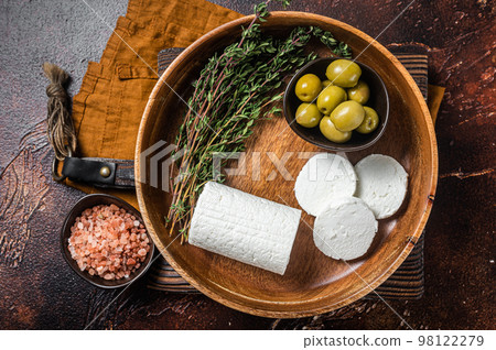 Soft Goat cheese chevre in a plate with thyme and olives. Dark background. Top view Soft Goat cheese chevre in a plate with thyme and olives. Dark background. Top view 98122279