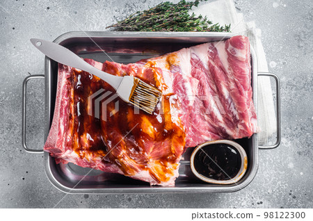 Cooking of Raw pork spare ribs with barbecue sauce. Gray background. Top view Cooking of Raw pork spare ribs with barbecue sauce. Gray background. Top view 98122300