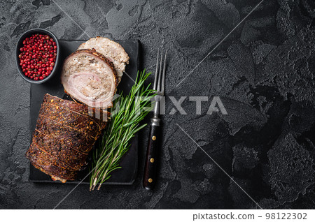 Baked pork roulade Porchetta, rolled pork meat on a marble board with herbs. Black background. Top view. Copy space Baked pork roulade Porchetta, rolled pork meat on a marble board with herbs. Black background. Top view. Copy space 98122302