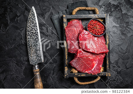 Uncooked Raw Venison dear meat, game meat. Black background. Top view 98122384