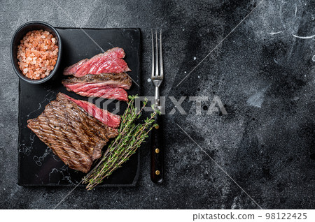 Grilled Wild Venison steak with thyme and salt, game meat. Black background. Top view. Copy space Grilled Wild Venison steak with thyme and salt, game meat. Black background. Top view. Copy space 98122425