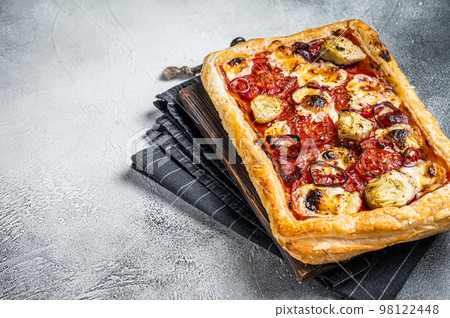 Vegetarian puff pastry pizza with artichoke, mozzarella, tomatoes and cheese. White background. Top view. Copy space 98122448