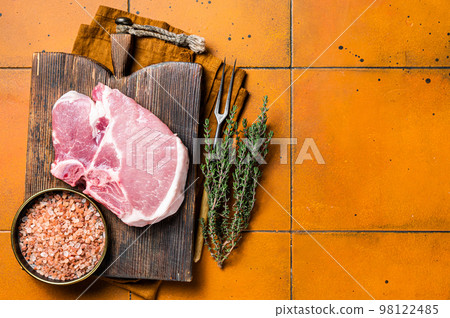 Fresh Raw pork t-bone chop meat steak on cutting board. Orange background. Top view. Copy space Fresh Raw pork t-bone chop meat steak on cutting board. Orange background. Top view. Copy space 98122485