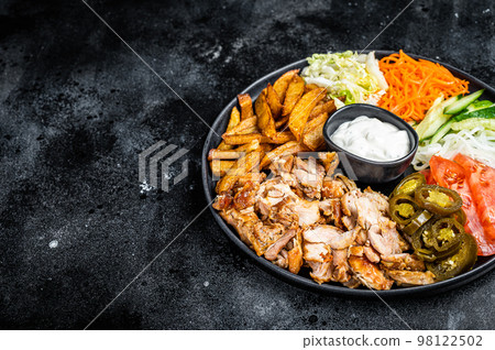 Shawarma Doner kebab on a plate with french fries and salad. Black background. Top view. Copy space 98122502