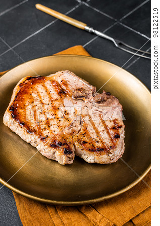BBQ fried pork T bone chop meat steak on a plate. Black background. Top view 98122519