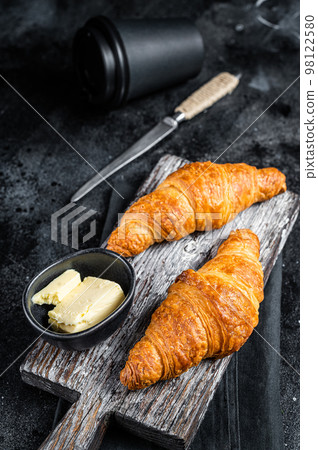 Fresh and tasty croissants with butter and cup of coffee. Black background. Top view 98122580