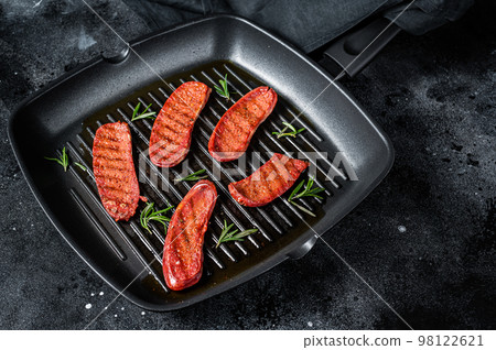 Fried Turkish Sucuk meat sausage on a grill skillet. Black background. Top view 98122621