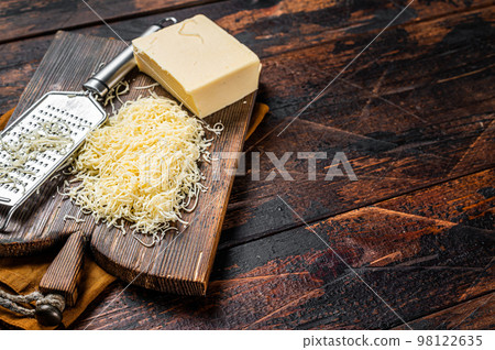 Piece of semi hard cheese and grated cheese with grater. Wooden background. Top view. copy space 98122635